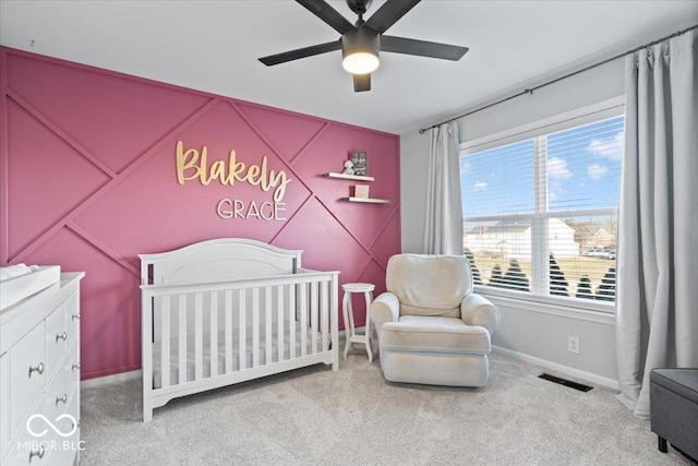 bedroom with visible vents, a crib, carpet, and a ceiling fan