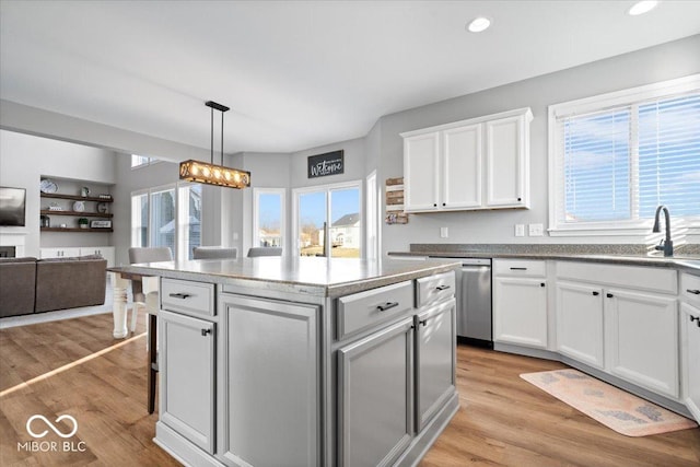 kitchen with a center island, open floor plan, dishwasher, light wood-style flooring, and a sink