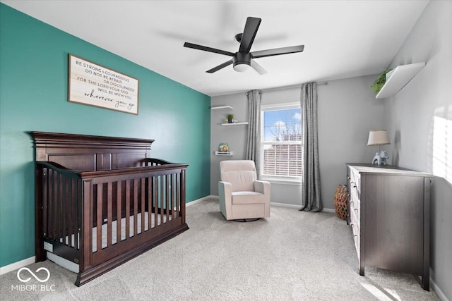 bedroom featuring carpet flooring, a crib, baseboards, and a ceiling fan