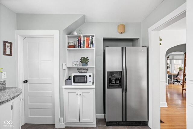 5426 Broadway St, Indianapolis, IN 46220 - kitchen featuring white microwave, stainless steel fridge with ice dispenser, arched walkways, white cabinetry, and dark wood-style floors