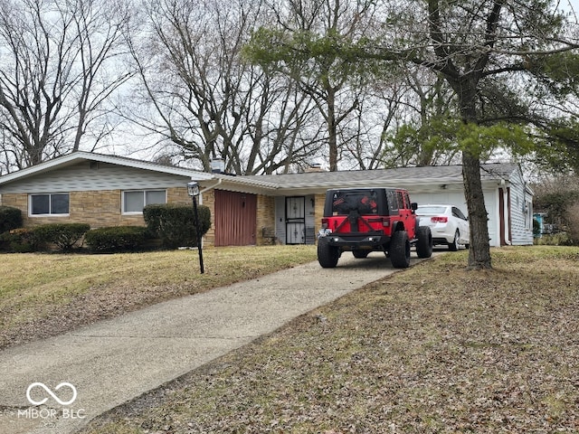 ranch-style home featuring stone siding, an attached garage, concrete driveway, and a front lawn