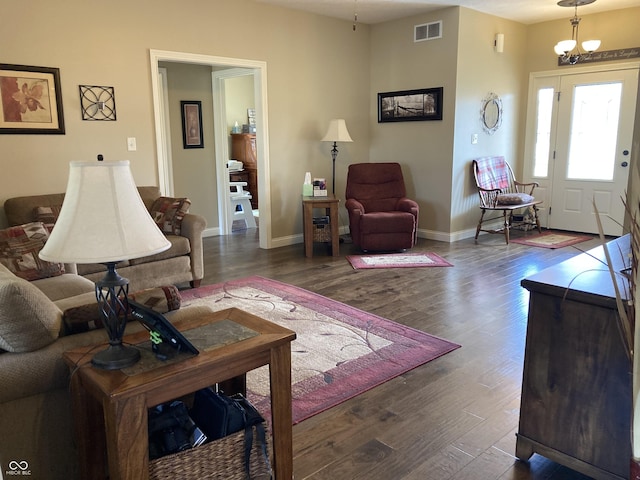 living area featuring wood finished floors, visible vents, a chandelier, and baseboards