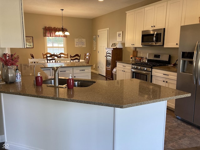 kitchen with a peninsula, stainless steel appliances, an inviting chandelier, white cabinetry, and a sink