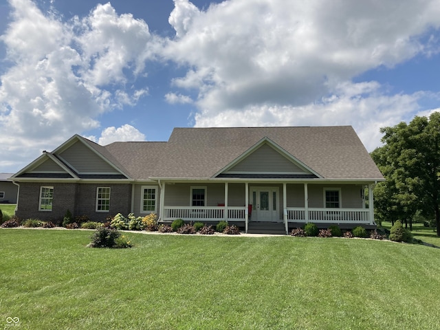 view of front facade featuring brick siding, a porch, a front lawn, and roof with shingles