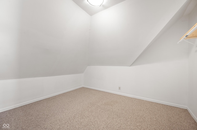 additional living space featuring baseboards, lofted ceiling, and carpet