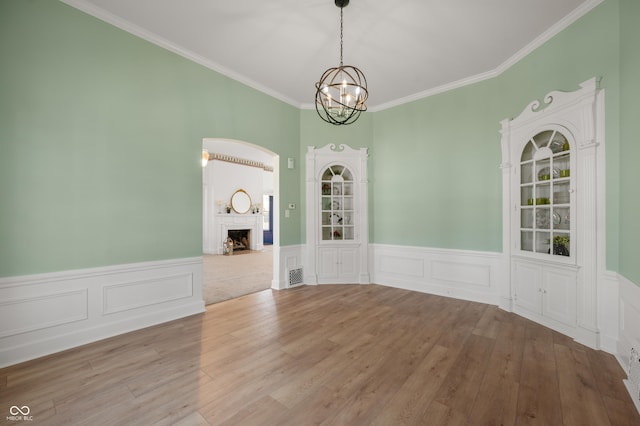 empty room featuring visible vents, wainscoting, a fireplace, an inviting chandelier, and wood finished floors