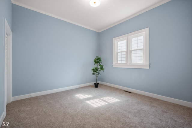 spare room with carpet floors, visible vents, baseboards, and ornamental molding