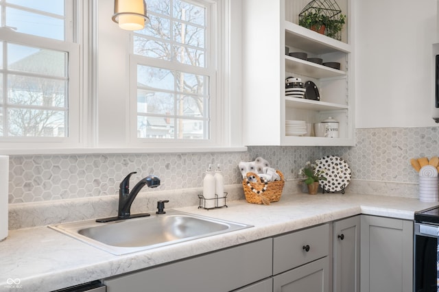 kitchen featuring decorative backsplash, a healthy amount of sunlight, open shelves, and a sink