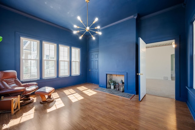 sitting room with a chandelier, crown molding, and wood finished floors