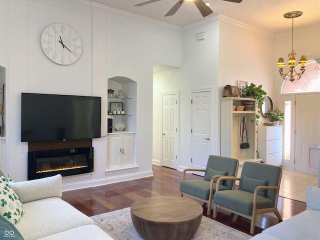 living room with built in shelves, wood finished floors, and ornamental molding