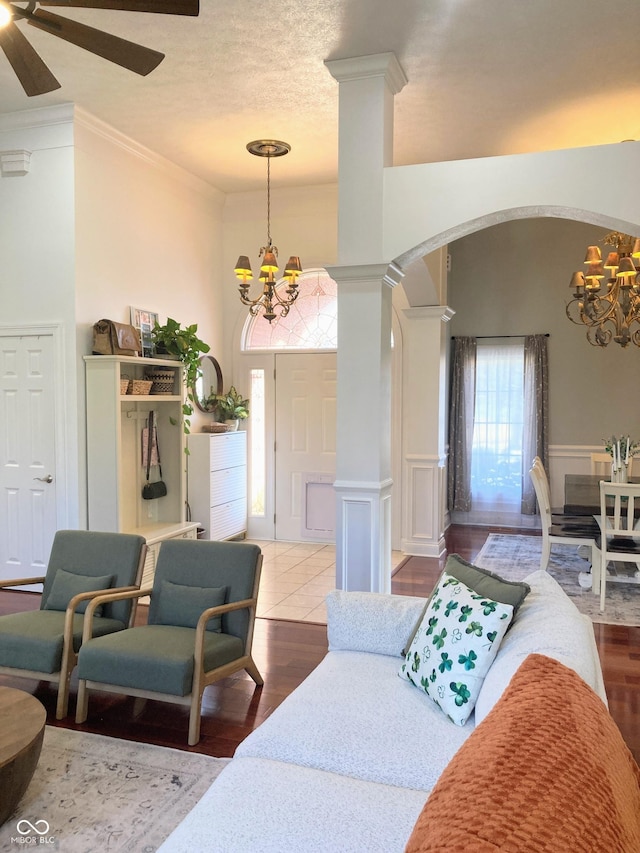 living room with arched walkways, wood finished floors, ornate columns, and ornamental molding