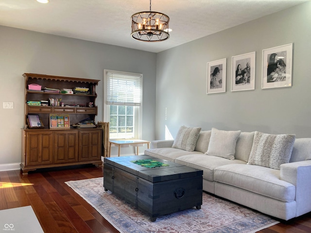 living room with dark wood-type flooring, a notable chandelier, and baseboards