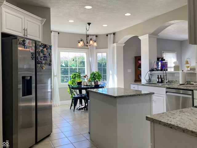 kitchen with light tile patterned flooring, a sink, white cabinets, appliances with stainless steel finishes, and a textured ceiling