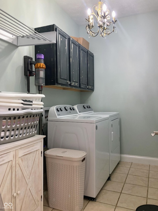 washroom featuring cabinet space, an inviting chandelier, light tile patterned floors, baseboards, and washing machine and clothes dryer