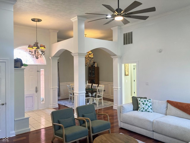 living room featuring visible vents, ornate columns, arched walkways, wainscoting, and a decorative wall