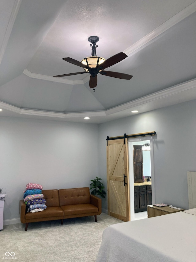 bedroom featuring a ceiling fan, a tray ceiling, a barn door, light colored carpet, and connected bathroom