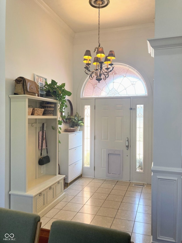 foyer featuring a high ceiling, light tile patterned floors, a chandelier, and ornamental molding