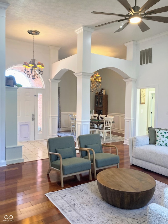 living area featuring visible vents, decorative columns, wood finished floors, arched walkways, and a decorative wall