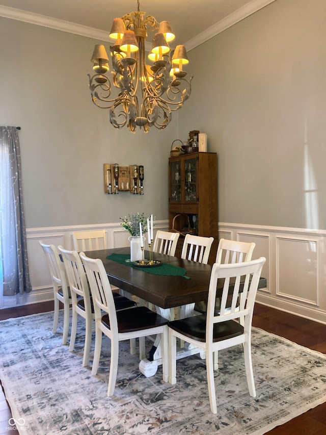 dining space featuring an inviting chandelier, wood finished floors, a wainscoted wall, and ornamental molding