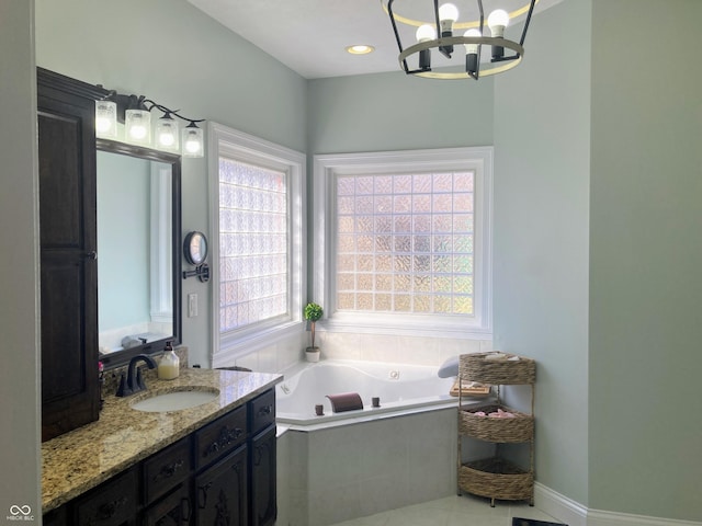 bathroom featuring baseboards, recessed lighting, an inviting chandelier, a tub with jets, and vanity