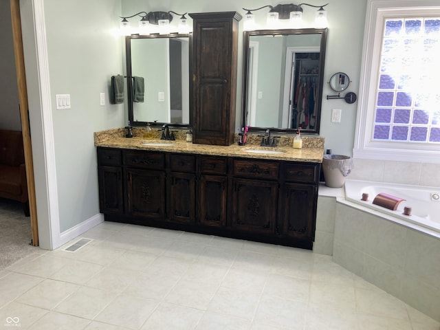 bathroom with double vanity, a bath, visible vents, and a sink