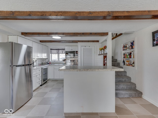 kitchen featuring a sink, white cabinets, wine cooler, appliances with stainless steel finishes, and beamed ceiling