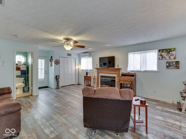 living room with a glass covered fireplace, light wood-style floors, and baseboards