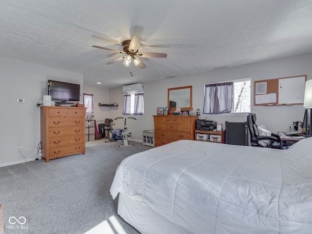 carpeted bedroom featuring baseboards, a textured ceiling, a wall unit AC, and a ceiling fan