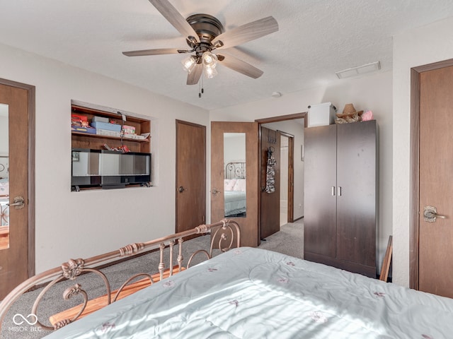 carpeted bedroom featuring visible vents, a textured ceiling, and ceiling fan