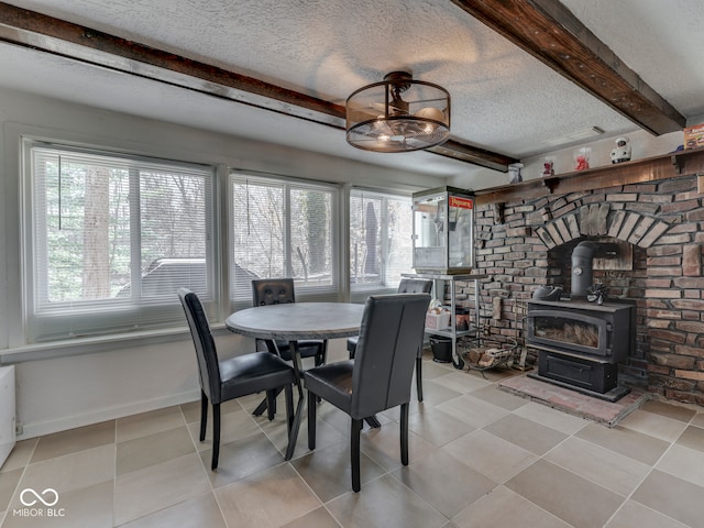 dining area featuring beam ceiling, a wood stove, light tile patterned flooring, and a textured ceiling