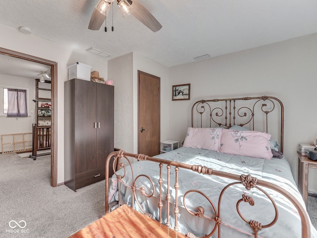 bedroom featuring carpet flooring, visible vents, a textured ceiling, and ceiling fan