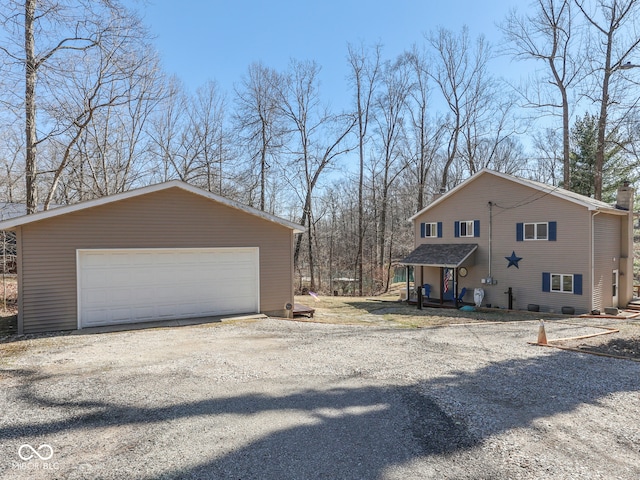 view of side of property with a garage, a chimney, and an outdoor structure