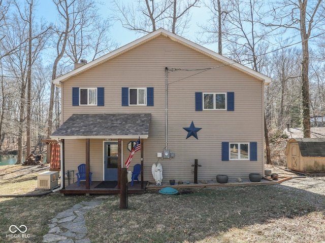 exterior space with ac unit, a shed, covered porch, an outdoor structure, and a shingled roof