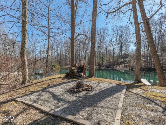 view of yard with a wooded view and a water view