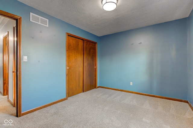 unfurnished bedroom featuring baseboards, visible vents, a closet, a textured ceiling, and carpet flooring