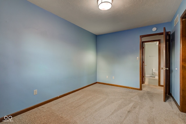 spare room featuring visible vents, light colored carpet, a textured ceiling, and baseboards