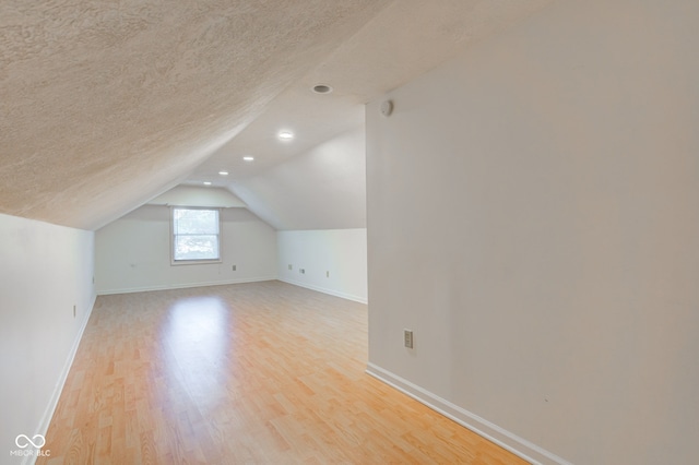 bonus room featuring baseboards, lofted ceiling, recessed lighting, light wood-style floors, and a textured ceiling