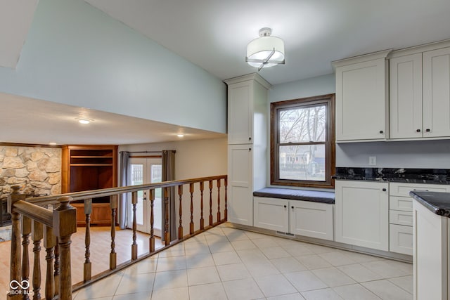 kitchen featuring a wealth of natural light, light tile patterned flooring, and dark stone countertops