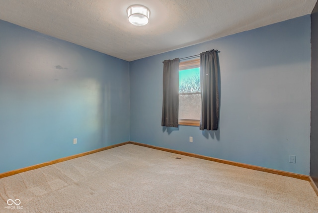 carpeted empty room featuring a textured ceiling and baseboards