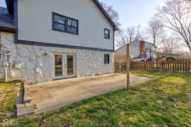 rear view of property with a yard, stone siding, fence, and a patio area