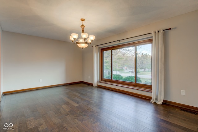 spare room with visible vents, baseboards, a chandelier, and dark wood finished floors