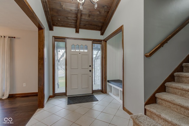 entrance foyer featuring baseboards, lofted ceiling with beams, light tile patterned flooring, stairs, and wood ceiling