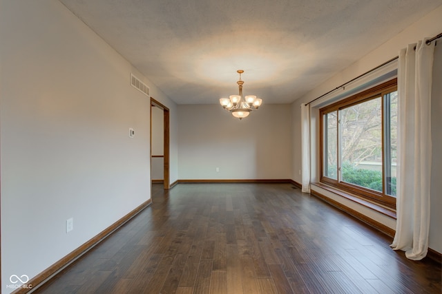 unfurnished room featuring visible vents, baseboards, dark wood finished floors, a notable chandelier, and a textured ceiling