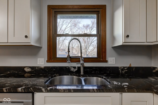 kitchen featuring a sink, dark stone counters, and white cabinetry