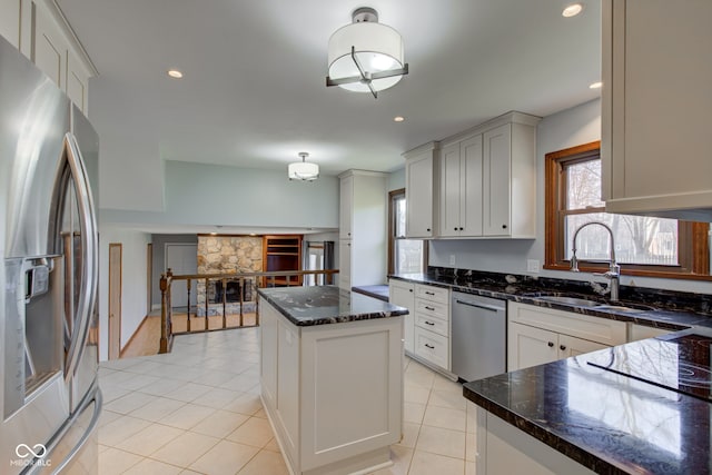 kitchen featuring a sink, dark stone countertops, a center island, stainless steel appliances, and light tile patterned flooring