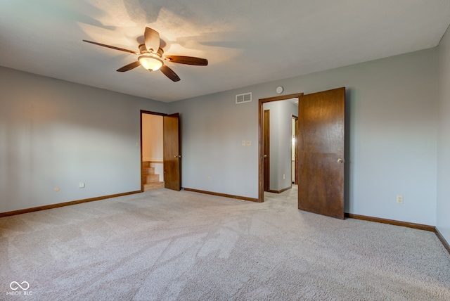 empty room with light carpet, a ceiling fan, visible vents, and baseboards