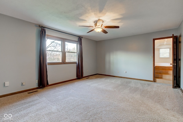 spare room with light carpet, visible vents, baseboards, and ceiling fan