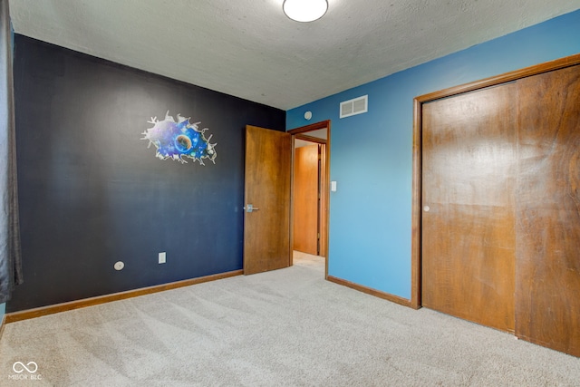 unfurnished bedroom featuring baseboards, visible vents, a closet, a textured ceiling, and carpet flooring