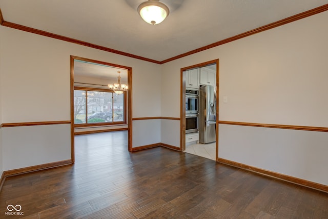 spare room featuring a chandelier, crown molding, baseboards, and wood finished floors