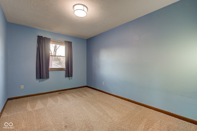 carpeted spare room with baseboards and a textured ceiling